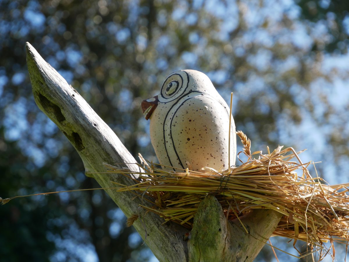 Ceramic bird on driftwood in the well-kept garden on the Lower Rhine